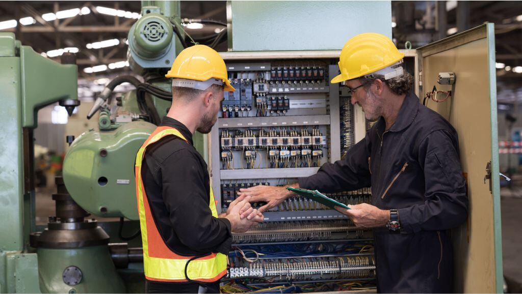 profissionais de manutenção preventiva e corretiva operando máquina industrial