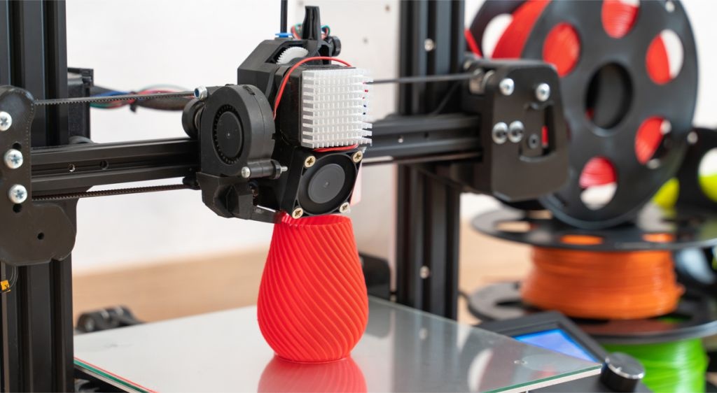 impressora 3D e carreteis de filamento multicoloridos representando como ganhar dinheiro com impressora 3d