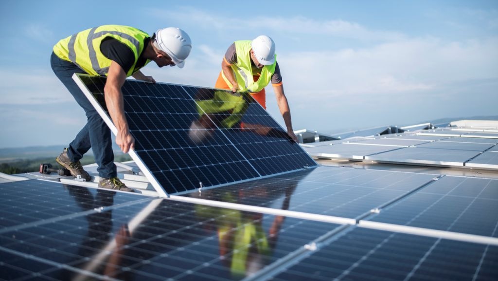 Dois engenheiros instalando painéis solares no telhado, solução para garantir mais eficiência energética