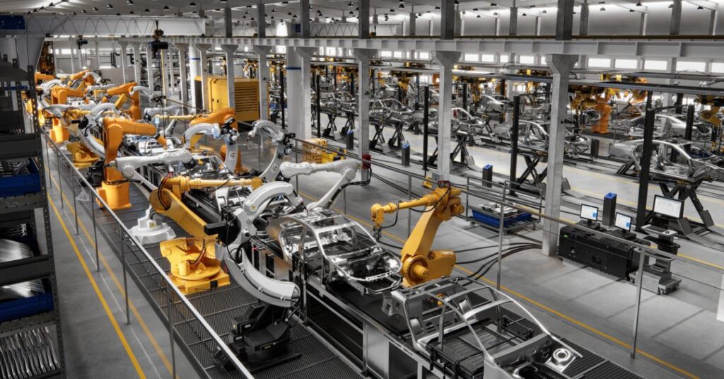 Linha de produção de automóveis automatizada com vários braços mecânicos.